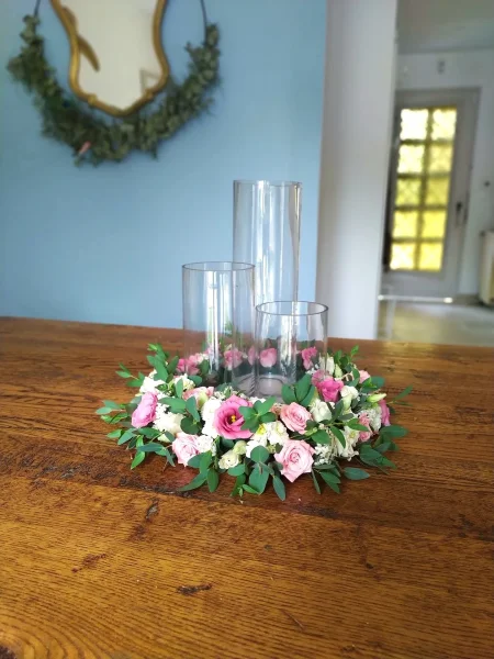 Centre de table champêtre élégant avec roses roses et blanches, eucalyptus, entourant trois vases en verre transparent pour un mariage.