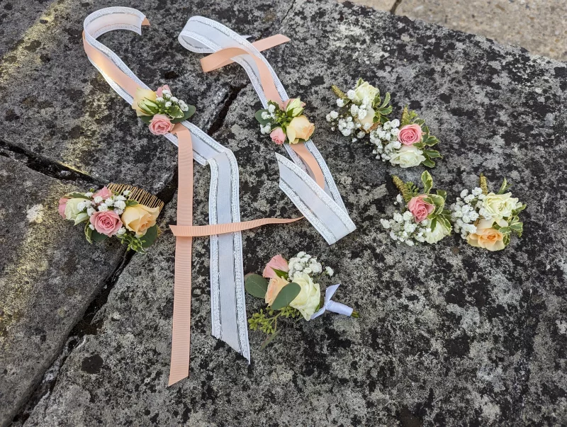 Assortiment d'accessoires floraux pour mariage: boutonniere, bracelet et peigne avec roses, gypsophile.
