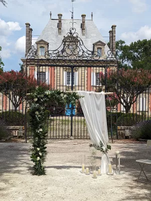 Arche florale champêtre élégante avec eucalyptus, roses blanches et drapé de tissu, pour une cérémonie de mariage en extérieur à Bordeaux.