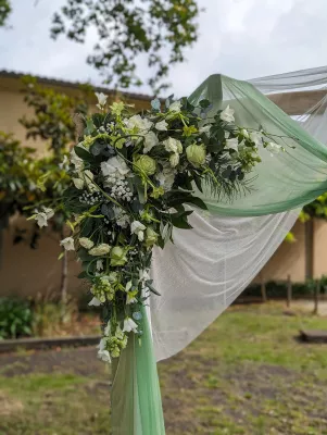 Décoration d'arche florale champêtre avec roses blanches, eucalyptus et branches d'olivier pour mariage d'été.