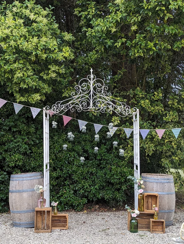 Arche florale champêtre pour photobooth avec eucalyptus, roses, gerberas roses et guirlandes, thème mariage.
