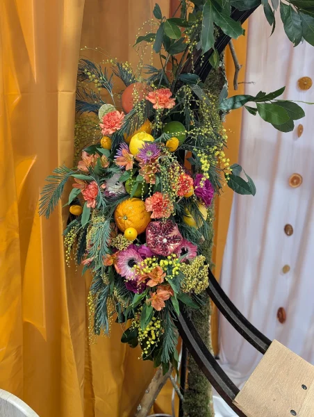 Arche florale exotique avec agrumes, grenades, mimosa, roses et alstroemeria pour decoration.