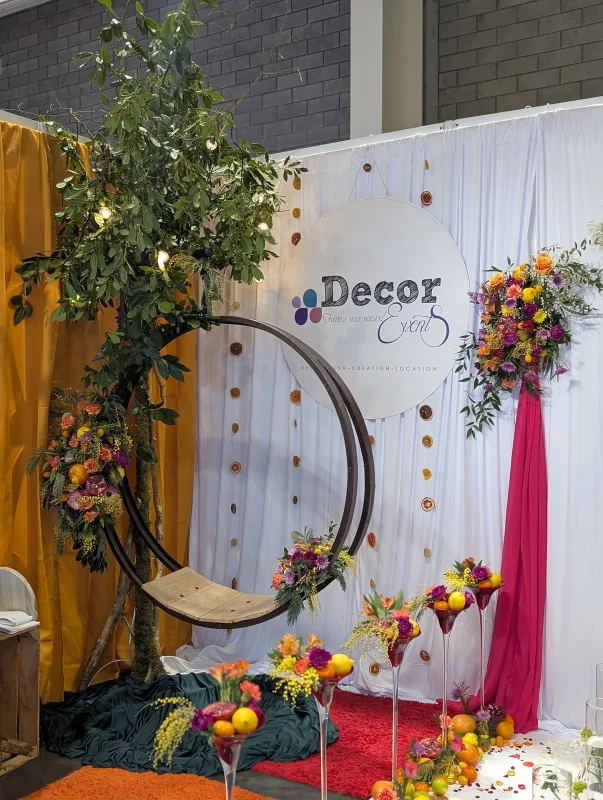 Vaste composition vegetale exotique avec fruits et fleurs colorees sur une structure d'arche pour mariage.
