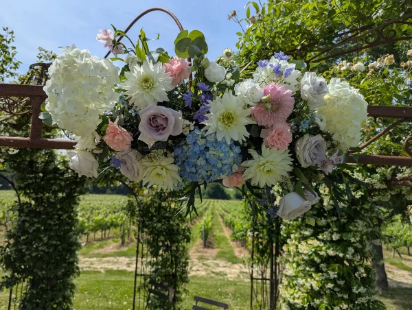 Arche florale champêtre avec hortensias blancs et bleus, dahlias, roses et feuillage vert au Château de Garde