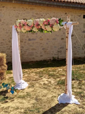 Arche florale champêtre avec hortensias blancs et roses, roses claires et feuillage vert pour mariage extérieur.