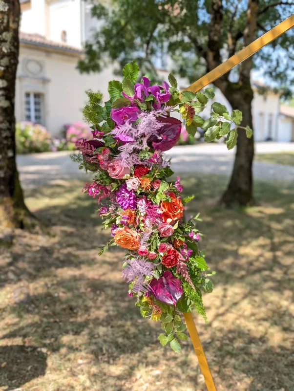 Geometric floral arch with purple orchids, orange roses and pink dahlias, sophisticated country style.