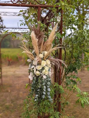 Arche florale bohème suspendue avec pampa, roses blanches et eucalyptus pour une cérémonie de mariage.