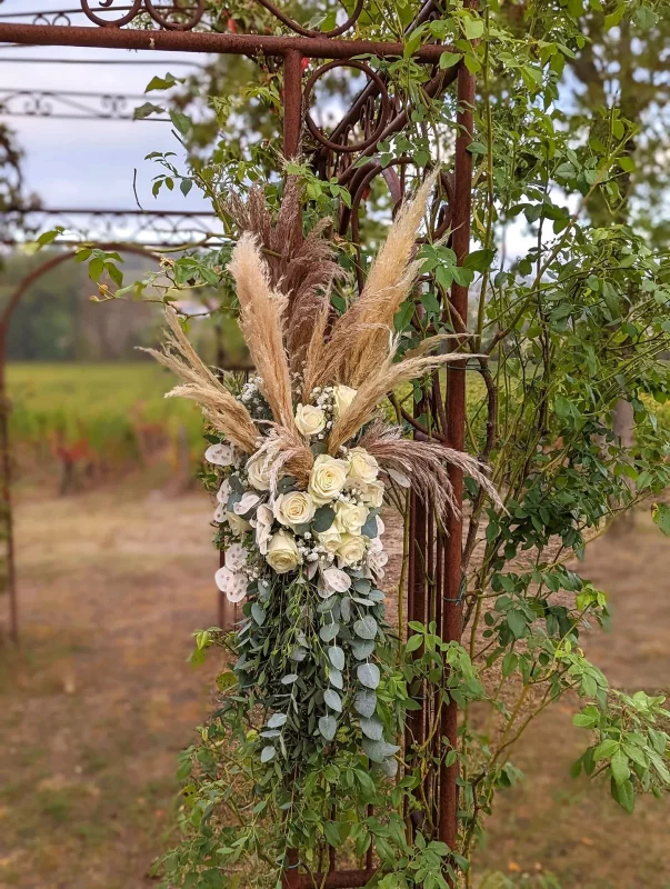 Arche florale bohème suspendue avec pampa, roses blanches et eucalyptus pour une cérémonie de mariage.