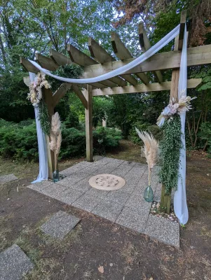 Arche de mariage bohème décorée de pampas, eucalyptus et fleurs séchées, sous une pergola en bois à Gauriac.