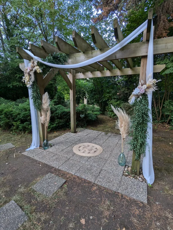 Bohemian wedding arch adorned with pampas, eucalyptus and dried flowers, under a wooden pergola in Gauriac.