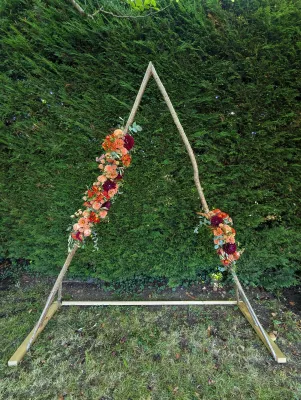 Arche florale de ceremonie boheme avec roses peches, dahlias prunes, pampas et feuillage vert.