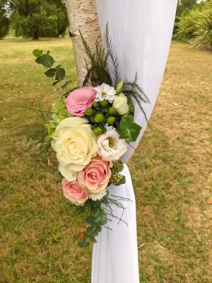 Composition florale d'arche de mariage champêtre avec roses, lisianthus et eucalyptus.