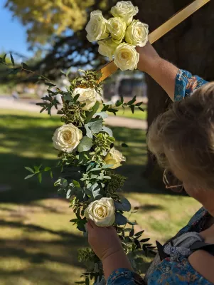 Création d'une arche florale moderne avec roses blanches et feuillage d'eucalyptus pour une cérémonie de mariage en extérieur.