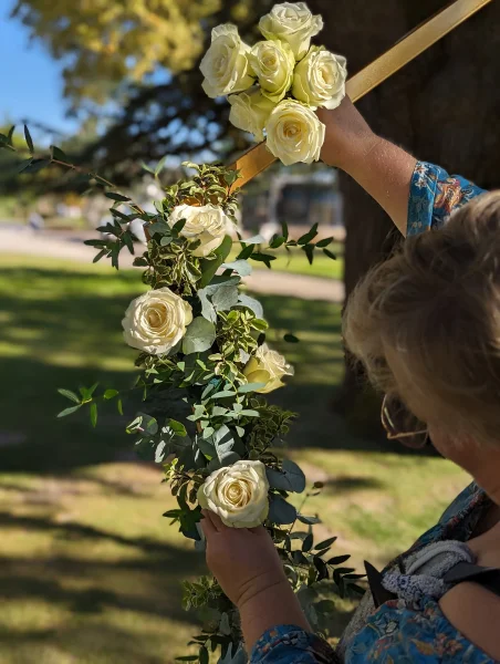Création d'une arche florale moderne avec roses blanches et feuillage d'eucalyptus pour une cérémonie de mariage en extérieur.