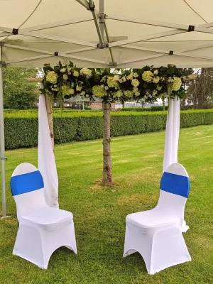 Arche florale classique en plein air pour cérémonie de mariage, ornée de roses crème, d'hortensias blancs et de feuillage verdoyant.