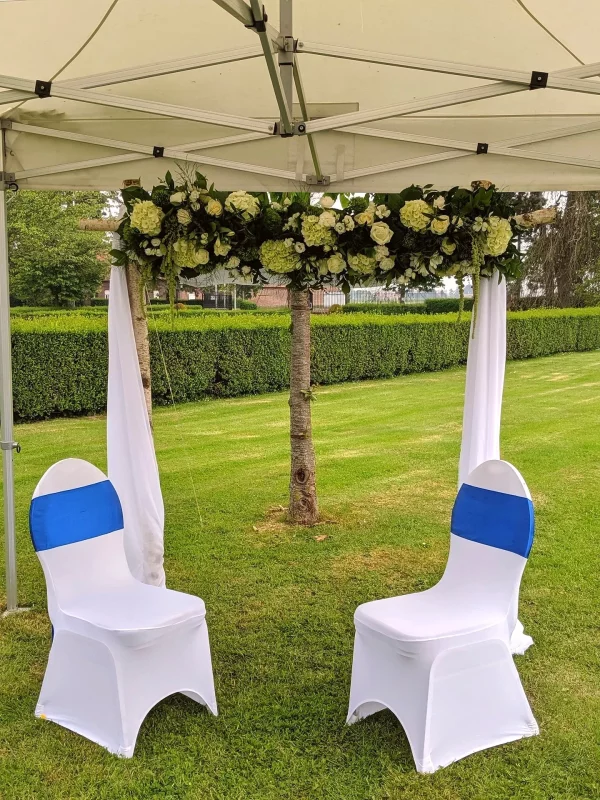 Arche florale classique en plein air pour cérémonie de mariage, ornée de roses crème, d'hortensias blancs et de feuillage verdoyant.