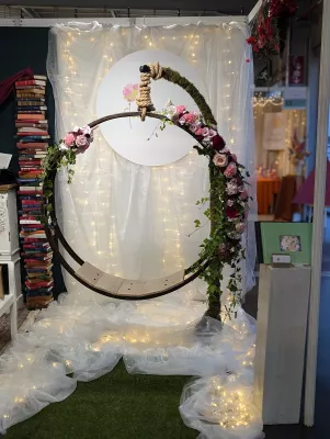 Arche florale ronde avec roses roses et lierre, style bohème, ambiance lumineuse pour un coin photo de mariage.
