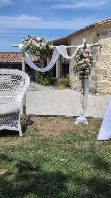 Sophisticated country-style floral arch with pink roses, white lisianthus, and eucalyptus for an outdoor wedding.