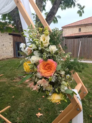 Arche florale hexagonale champêtre sophistiquée avec roses jaunes, oranges et feuillage panaché.