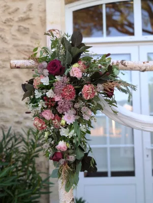 Detail of sophisticated rustic floral arrangement on arch with burgundy roses and pink carnations