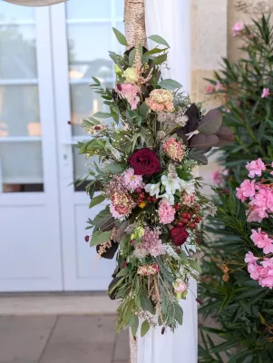 Detail of sophisticated rustic floral arrangement on arch with burgundy roses and pink carnations