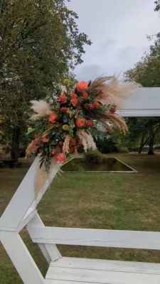 Sophisticated rustic floral arch with orange roses, pampas grass, and eucalyptus for an outdoor wedding.