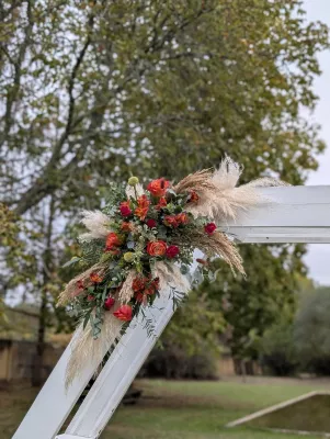 Sophisticated rustic floral arch with orange roses, pampas grass, and eucalyptus for an outdoor wedding.