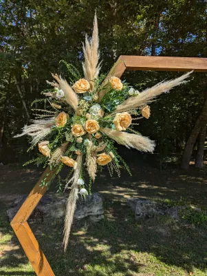Magnifique decoration d'arche de mariage boheme chic avec des roses peche, pampas et verdure, en exterieur.