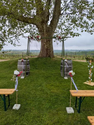 Arche florale champêtre et exotique avec roses blanches et fleurs rouges suspendues, cérémonie de mariage en extérieur.