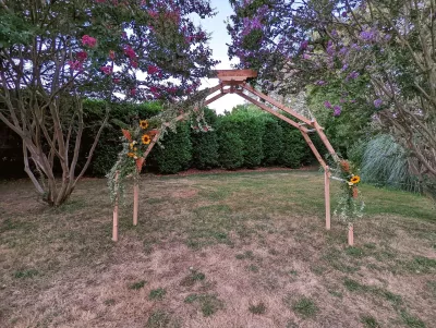 Arche florale champêtre pour mariage, décorée de tournesols, lierre et chardons.
