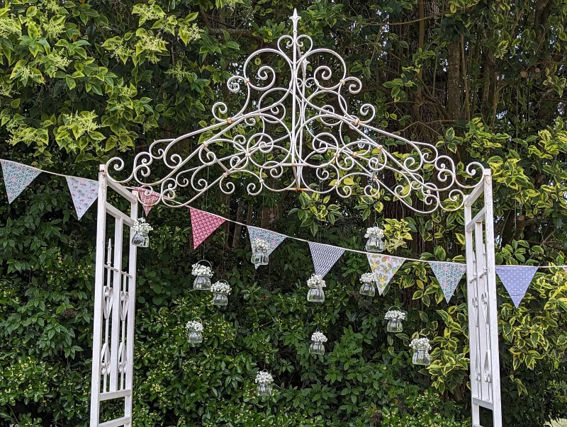 Detail of the country-style floral arch adorned with small hanging vases filled with pure white gypsophila.