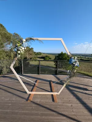 Arche de mariage hexagonale décorée de fleurs bleues et blanches, hortensias, roses et eucalyptus, style moderne champêtre.
