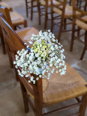 Gros plan d'une décoration de chaise de cérémonie avec gypsophila blanc et petites fleurs jaunes, style champêtre.