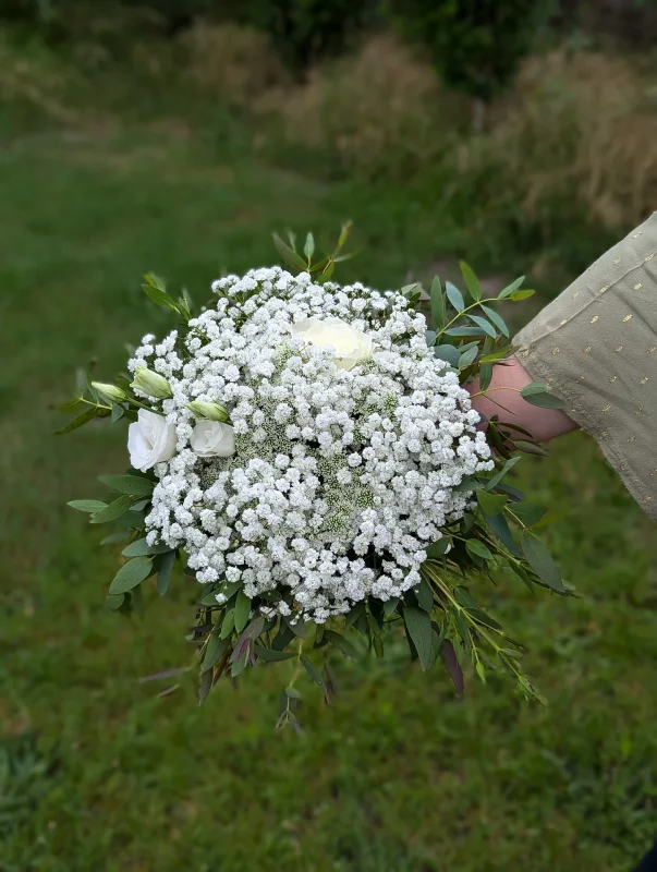 A small, country-chic toss bouquet for weddings, composed of white gypsophila, white roses, and green foliage.