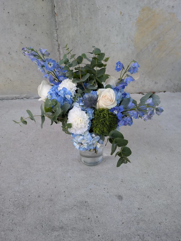 A delightful, rustic-inspired throwing bouquet featuring blue hydrangeas, white roses and thistles, perfect for a spring wedding.