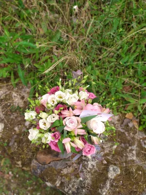 Joli bouquet à lancer de style champêtre avec lisianthus roses et blancs, roses et alstroemeria, sur fond de verdure.