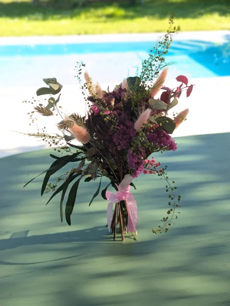 Petit bouquet à lancer champêtre avec pampa rose, eucalyptus et feuillages variés pour un mariage printanier.