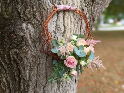 Bouquet de mariée à lancer bohème avec roses pâles, astilbe et eucalyptus, attaché à une couronne de brindilles.
