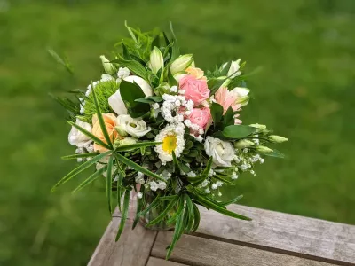Bouquet à lancer de mariage champêtre, composé de roses roses et pêche, lisianthus blancs et feuillage vert frais.