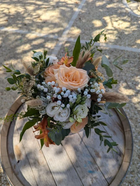 Bouquet de mariee boheme compose de roses peche, eustoma blanc, pampas et feuillage, pour un mariage d'automne.