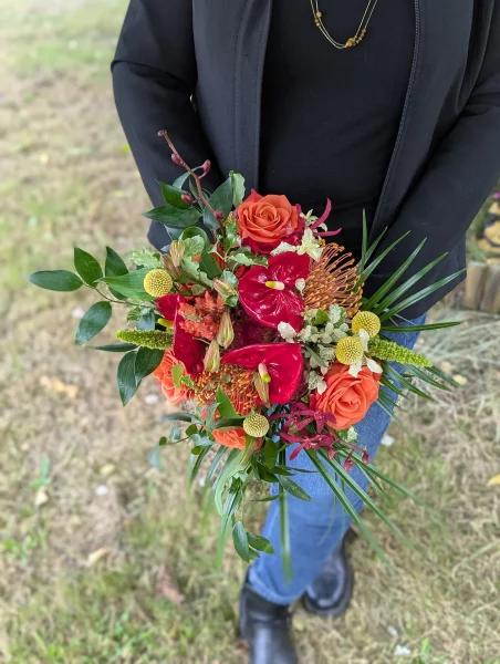Bouquet de mariée exotique avec anthurium rouge, roses orange et feuillage luxuriant pour le mariage de Valerie.