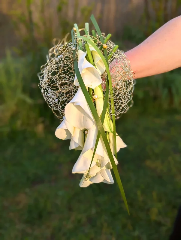 Modern bridal bouquet with cascading white calla lilies, structured with golden netting and pearls for an elegant wedding.