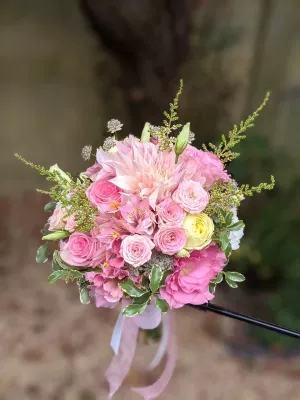 Bouquet de mariée bohème avec un grand dahlia rose poudré, des roses de différentes teintes et un feuillage verdoyant.