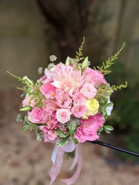 Bouquet de mariée bohème avec un grand dahlia rose poudré, des roses de différentes teintes et un feuillage verdoyant.