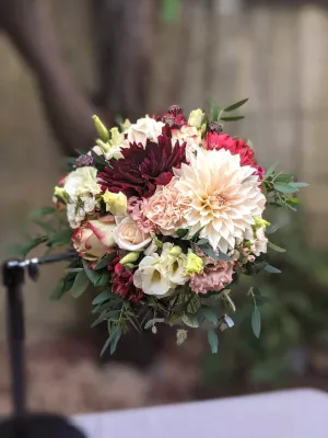 Bouquet de mariee rond et champetre avec dahlias bordeaux et creme, roses, oeillets peche et feuillage frais eucalyptus.