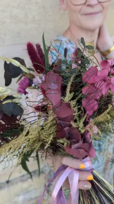 Sophisticated rustic bridal bouquet with burgundy eucalyptus, green ferns, and gilded grasses for Emma & Valient wedding.