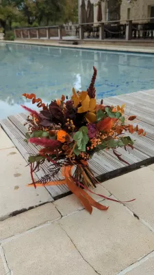 Bohemian botanical bridal bouquet with dried orange flowers, eucalyptus, and ferns for an autumn wedding.