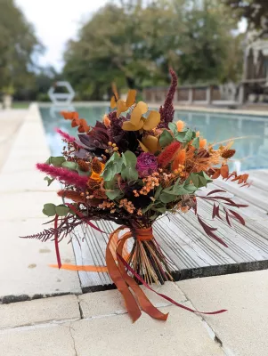 Bohemian botanical bridal bouquet with dried orange flowers, eucalyptus, and ferns for an autumn wedding.