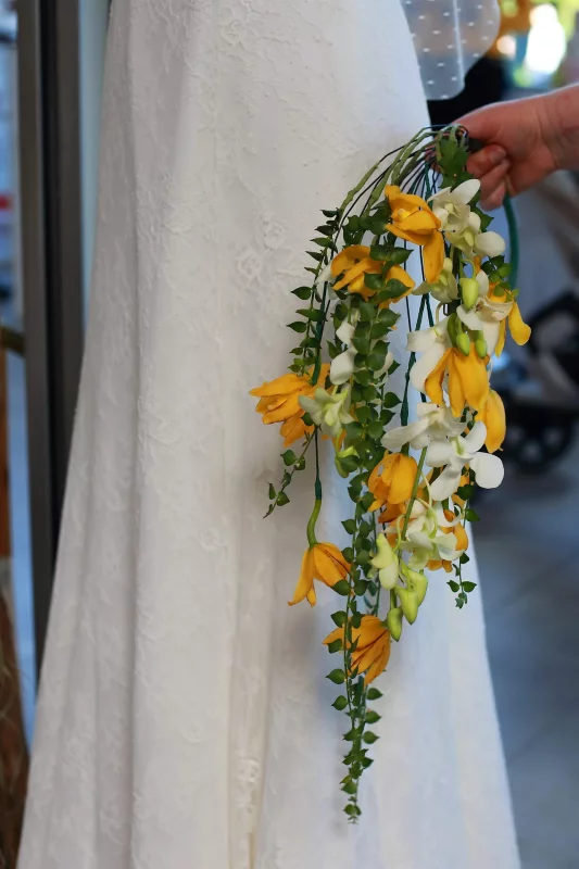 Bouquet de mariée cascade élégant avec freesias jaunes et blancs, et feuillage vert retombant.
