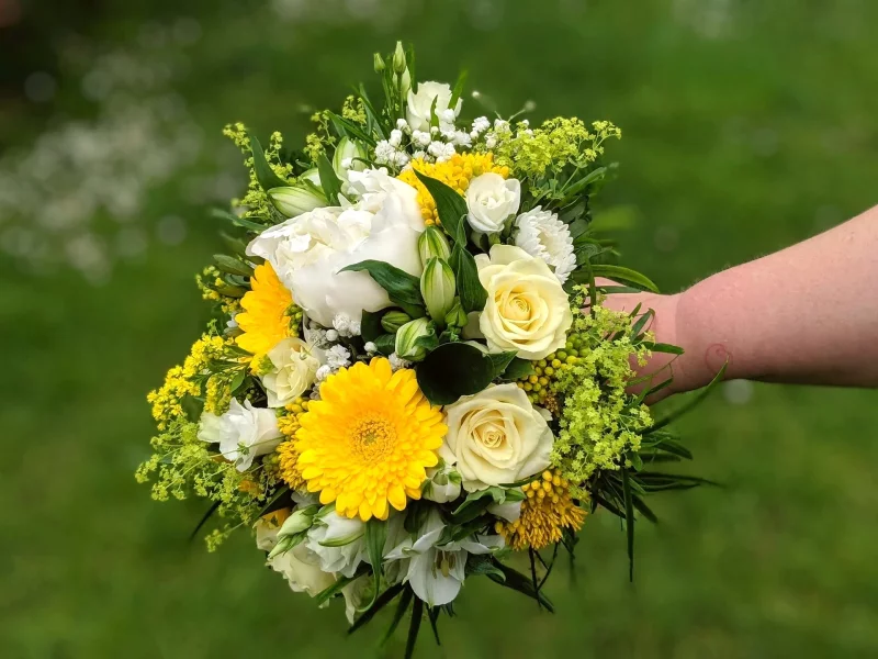 Magnifique bouquet de mariée champêtre avec pivoines blanches, gerberas jaunes éclatants et roses crémeuses pour un mariage printanier.